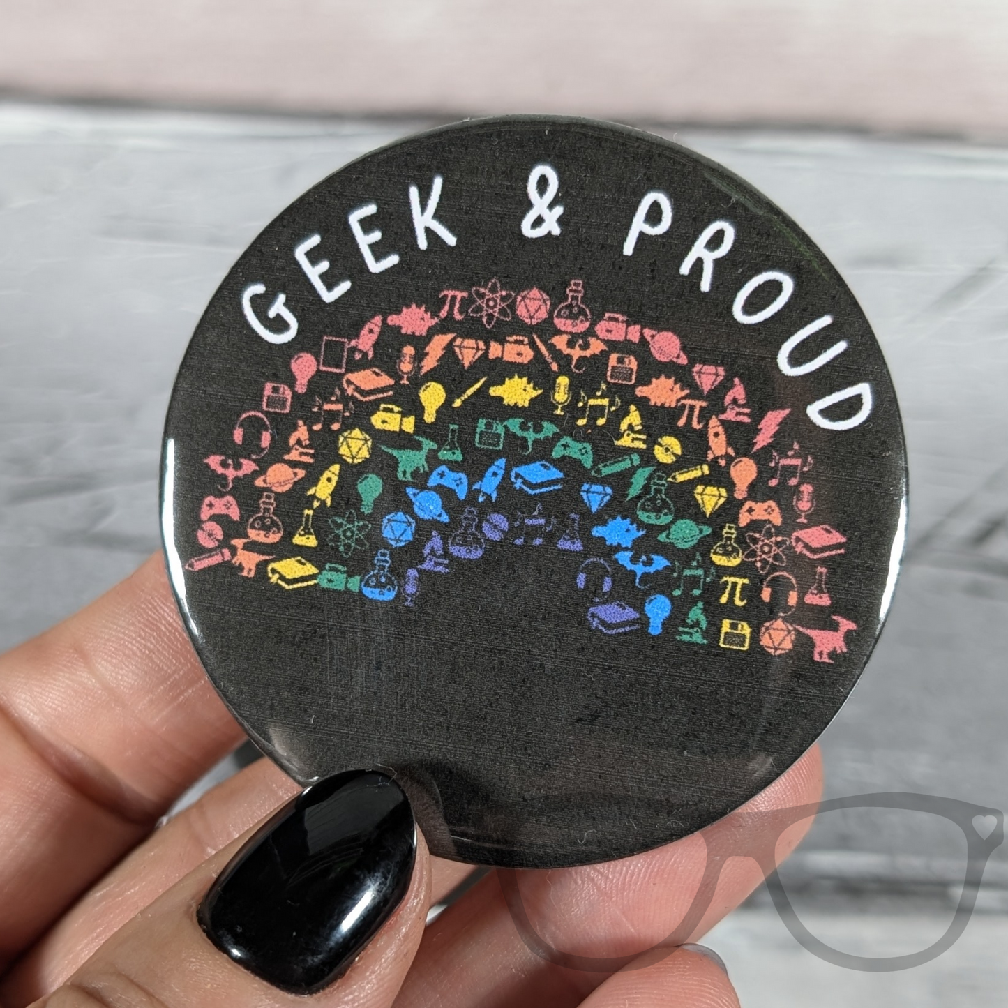 Person holding a Geek and Proud badge with a rainbow design, perfect for science, computing, and space fans.