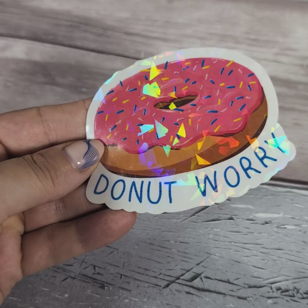 Video showcasing the crackled glass effect of the Donut Worry sparkling vinyl sticker, adding a unique shine to its bright pink donut design.