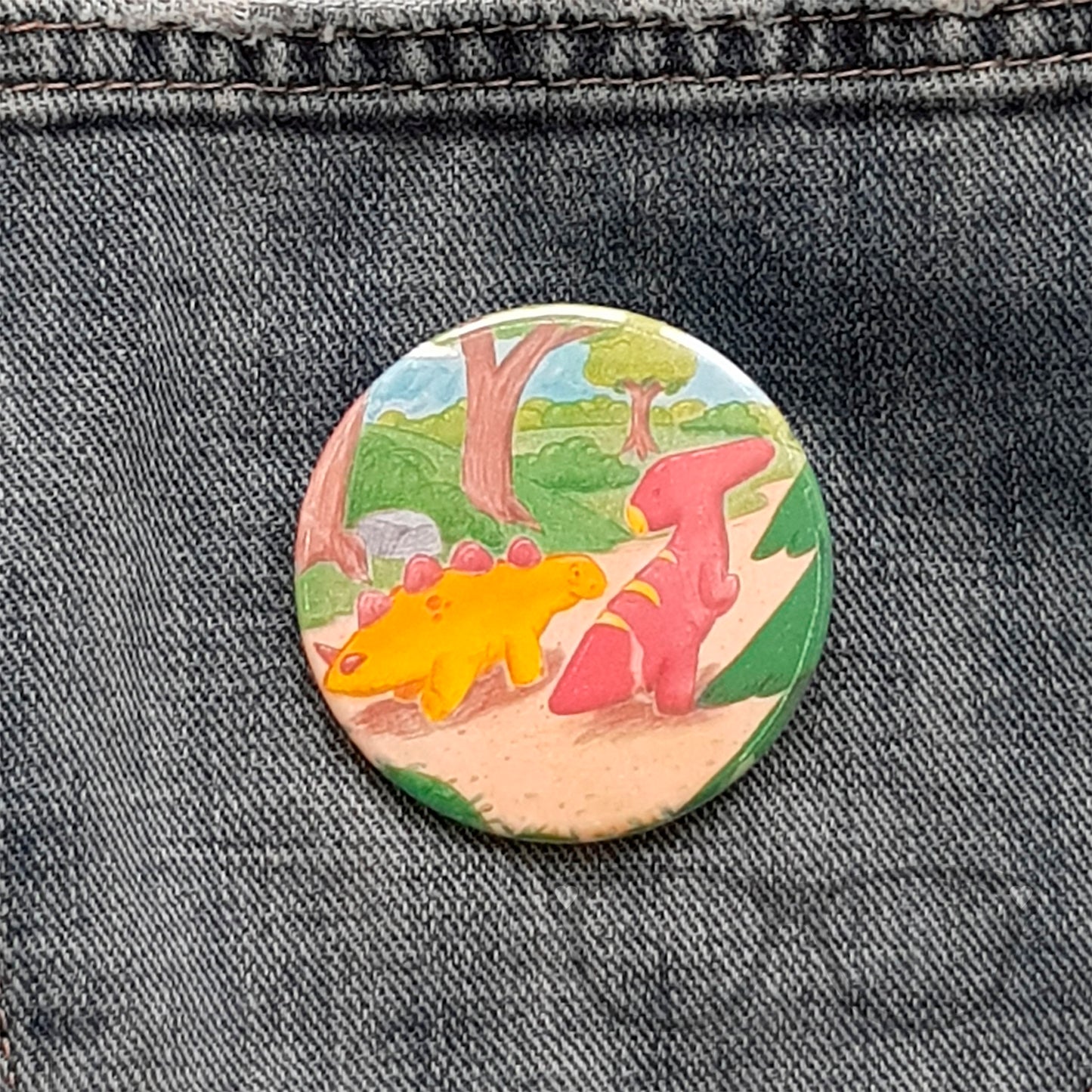 This 58mm badge shows the illustration of Derek and Irene the dinosaurs starting off on their adventure.