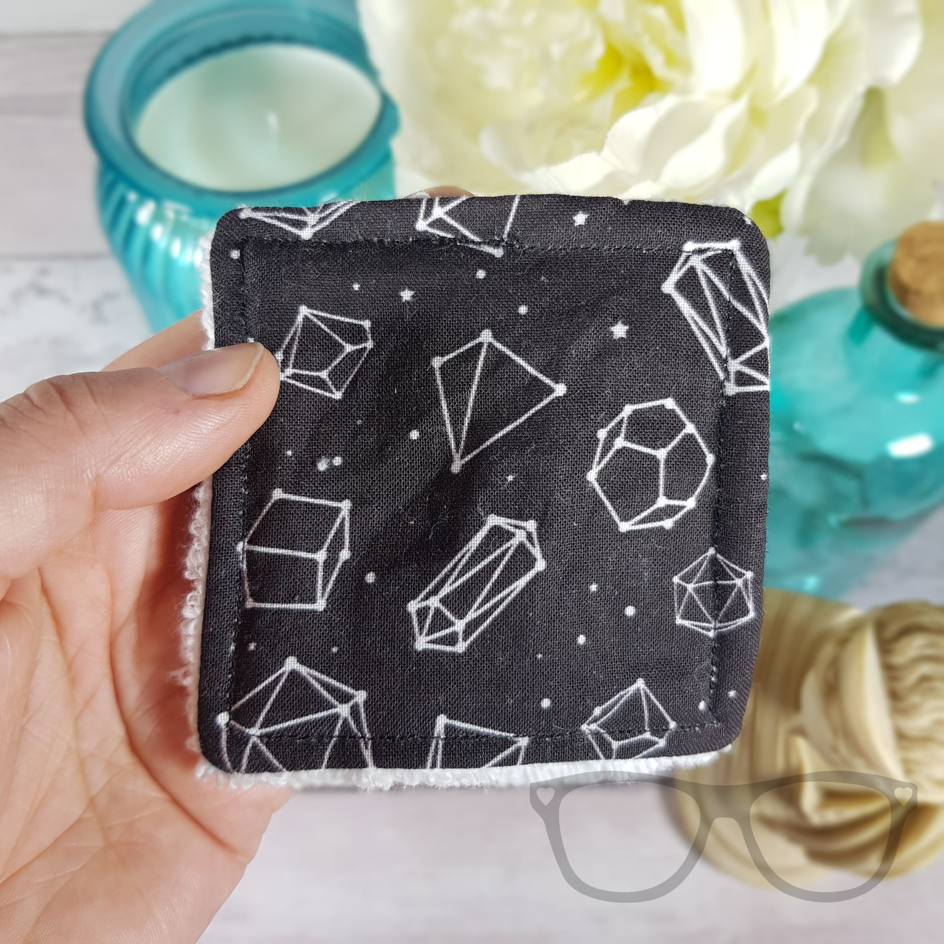 Close up of square reusable face wipe showing exclusively designed fabric of dice constellations.