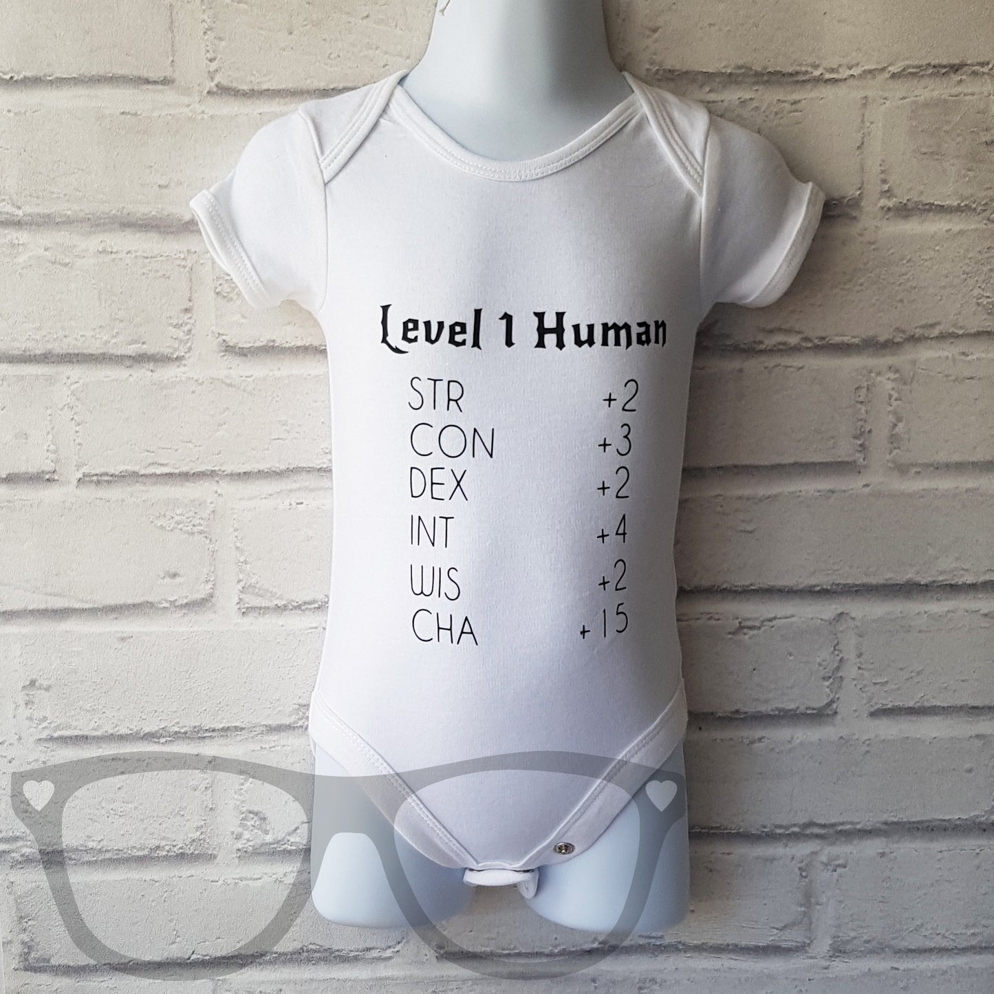 Level 1 human baby body suit. White organic cotton baby suit with popper detail. Heat pressed black vinyl design on the front that shows Level 1 and appropriate stats for a baby. Great gift idea for new geeky parents who love to play dungeons and dragons