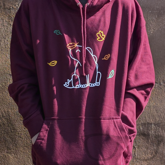 Burgundy Hoodie with kangaroo pocket for Autumn featuring Derek the Stegosaurus sitting amongst the falling autumn leaves