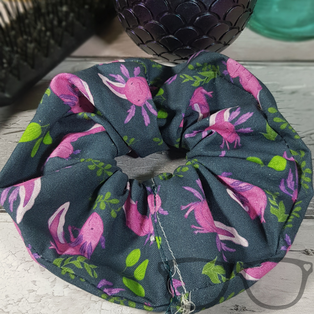 Pink Axolotl pattern on a dark green background handmade scrunchie