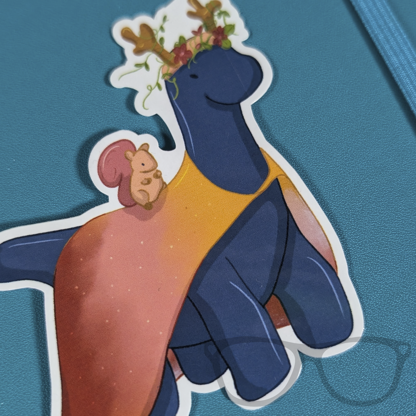 Extreme close-up of Brenda the Druid Brachiosaurus vinyl sticker on a notebook, highlighting the intricate details of this magical, nature-inspired design.