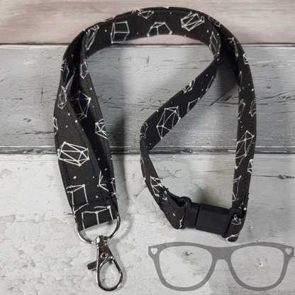 Dice Constellation Lanyard, black fabric with white dice in a constellation pattern. The lanyard features a lobster style clip for your keys or ID Card, and a quick release safety clip