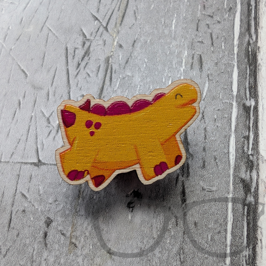 Wooden pin showing a full colour design of Derek the yellow stegosaurus