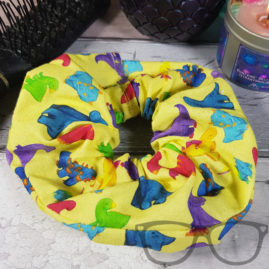 Hair scrunchie with fun and bright dinosaur pattern using original illustrations on a bright yellow background
