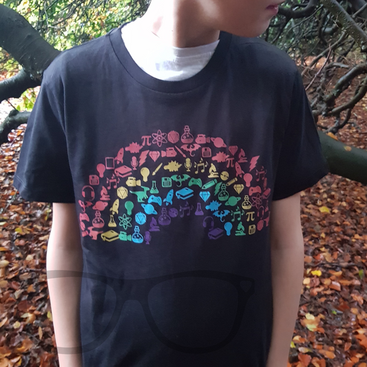 Young model proudly wearing the Geek and Proud T-shirt with a rainbow design featuring geek icons like game controllers, dice, and dinosaurs.