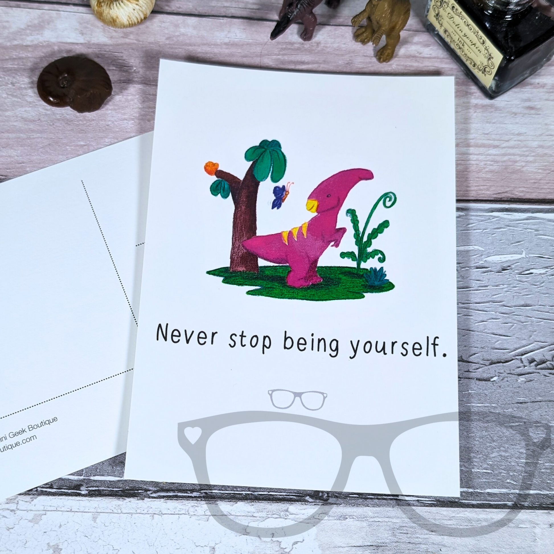 Never stop being yourself postcard featuring Irene the dinosaur on a white background