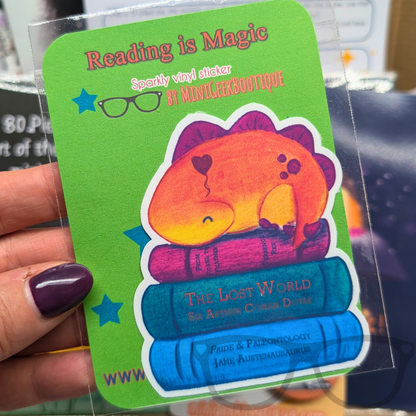  A charming vinyl sticker featuring Derek the stegosaurus snoozing on a book pile. A perfect reward for young readers and book lovers.
