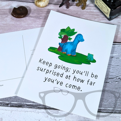 Keep going postcard showing Brenda the Brachiosaurus on the glossy side and the matt, writable side