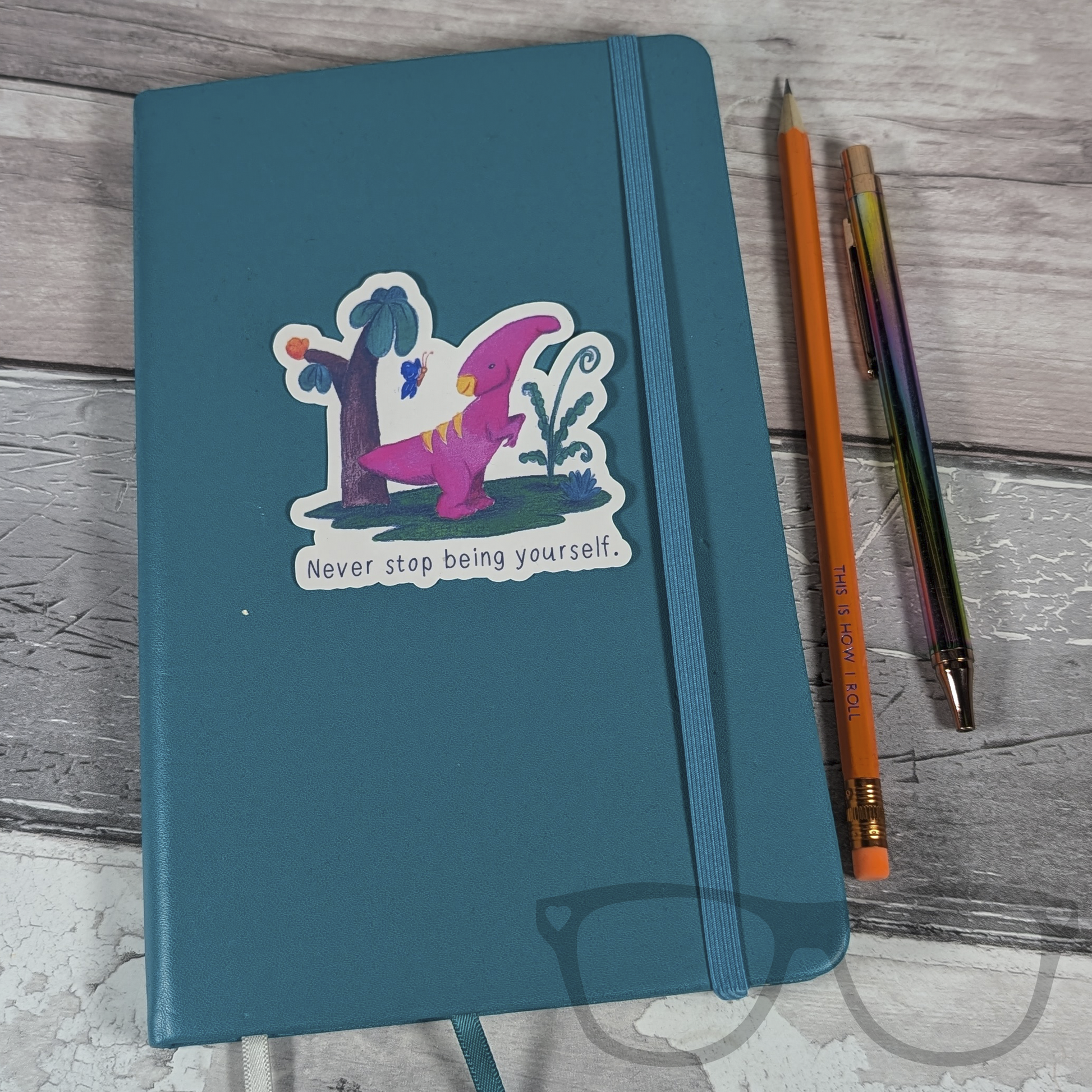  Irene the Parasaurolophus "Never stop being yourself" sticker placed on a notebook, adding a positive and inspirational touch to your workspace or study materials.