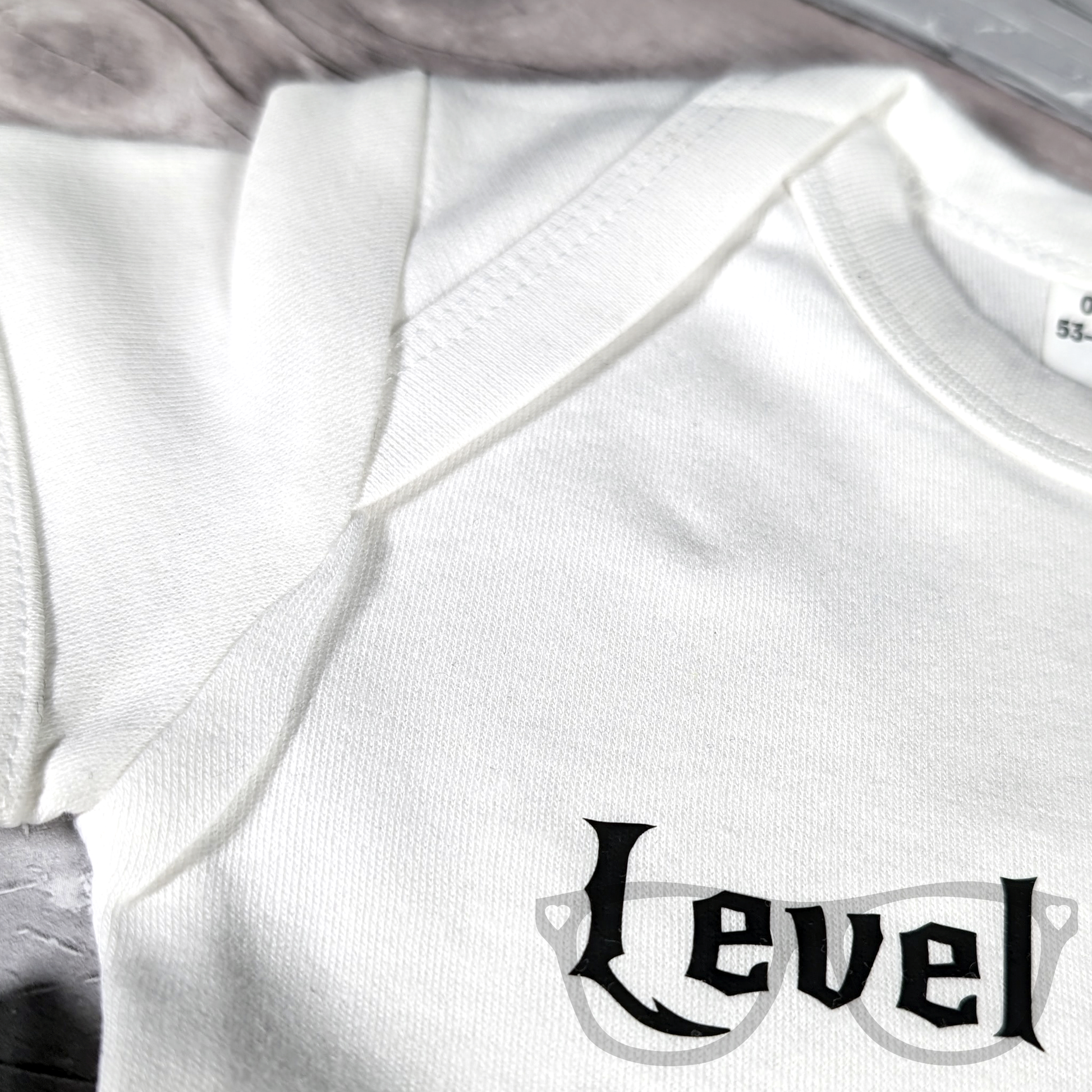 Dungeons & Dragons-inspired baby bodysuit with Level 1 Human design showing envelope sleeve for easy changes