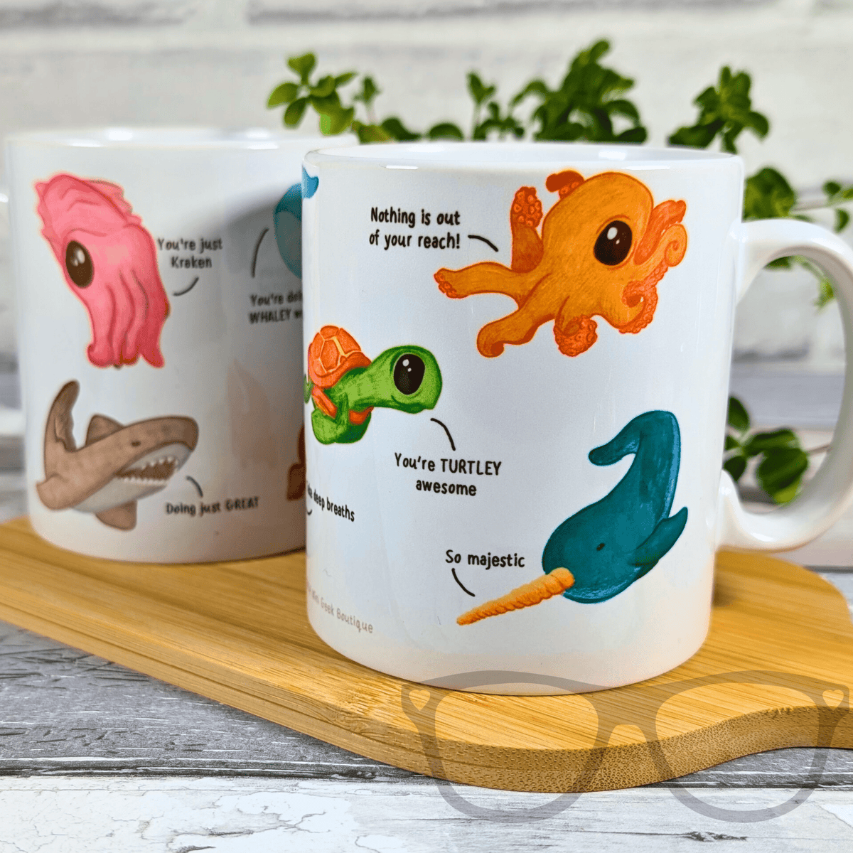 Two mugs with cartoon sea creatures and humorous text on a wooden tray.