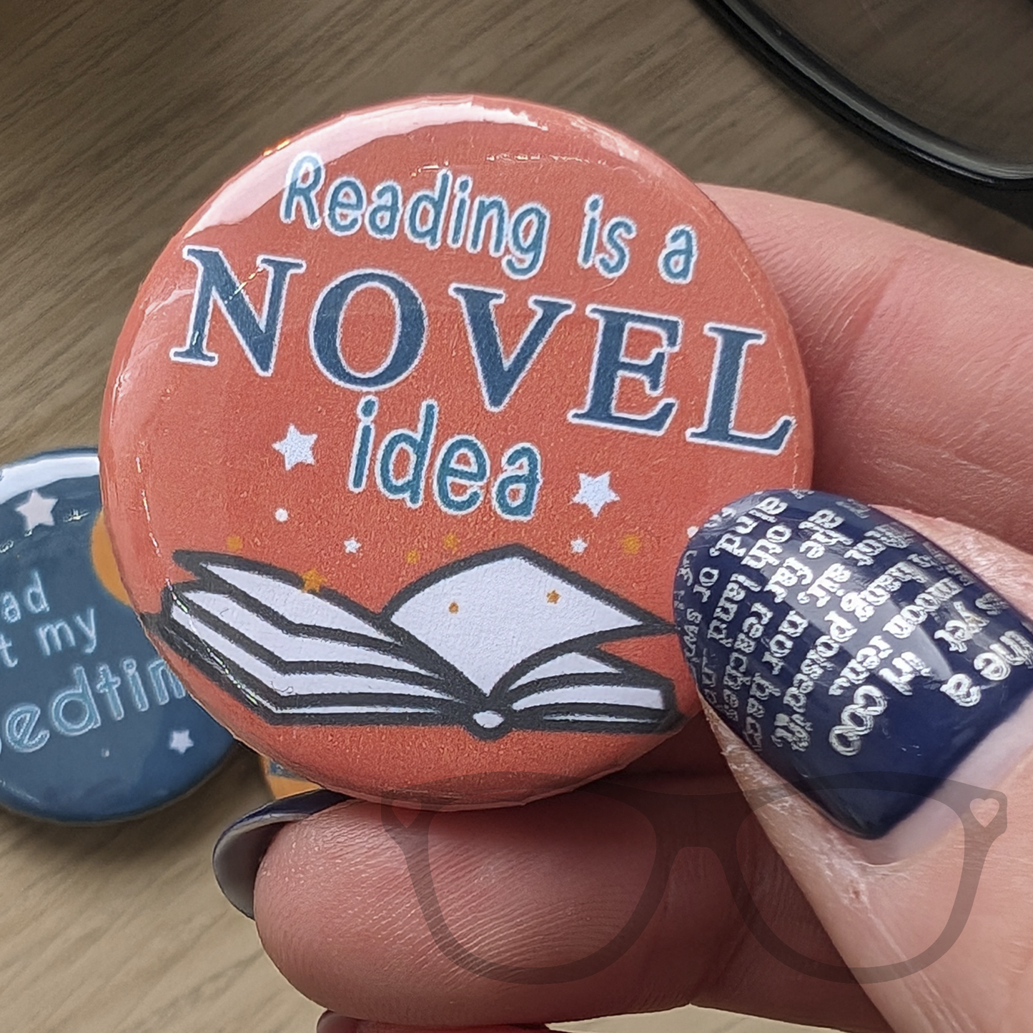 Reading is a novel idea, orange badge with green text and an open book graphic