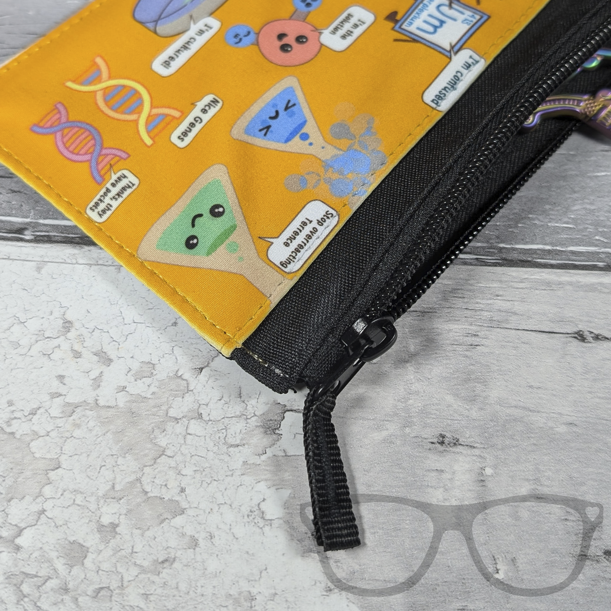 Close up zip detail of science pencil case yellow pencil case case with cute kawaii illustrations of science puns
