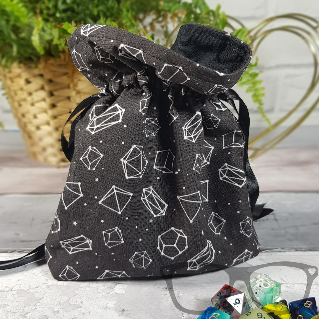 White dice constellations on a black background, lined with a black fabric and secured with a black ribbon.