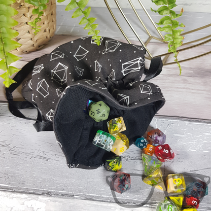 White dice constellations on a black background, lined with a black fabric and secured with a black ribbon. Dice not included