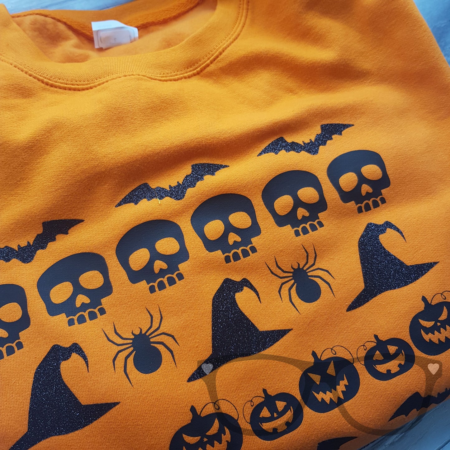 Close up of the Halloween Sweater showing the glitter and black vinyl graphics