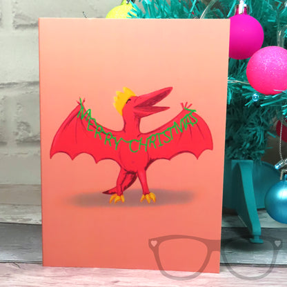 Pink Christmas card with Pterry the Pteranodon holding Merry Christmas garland
