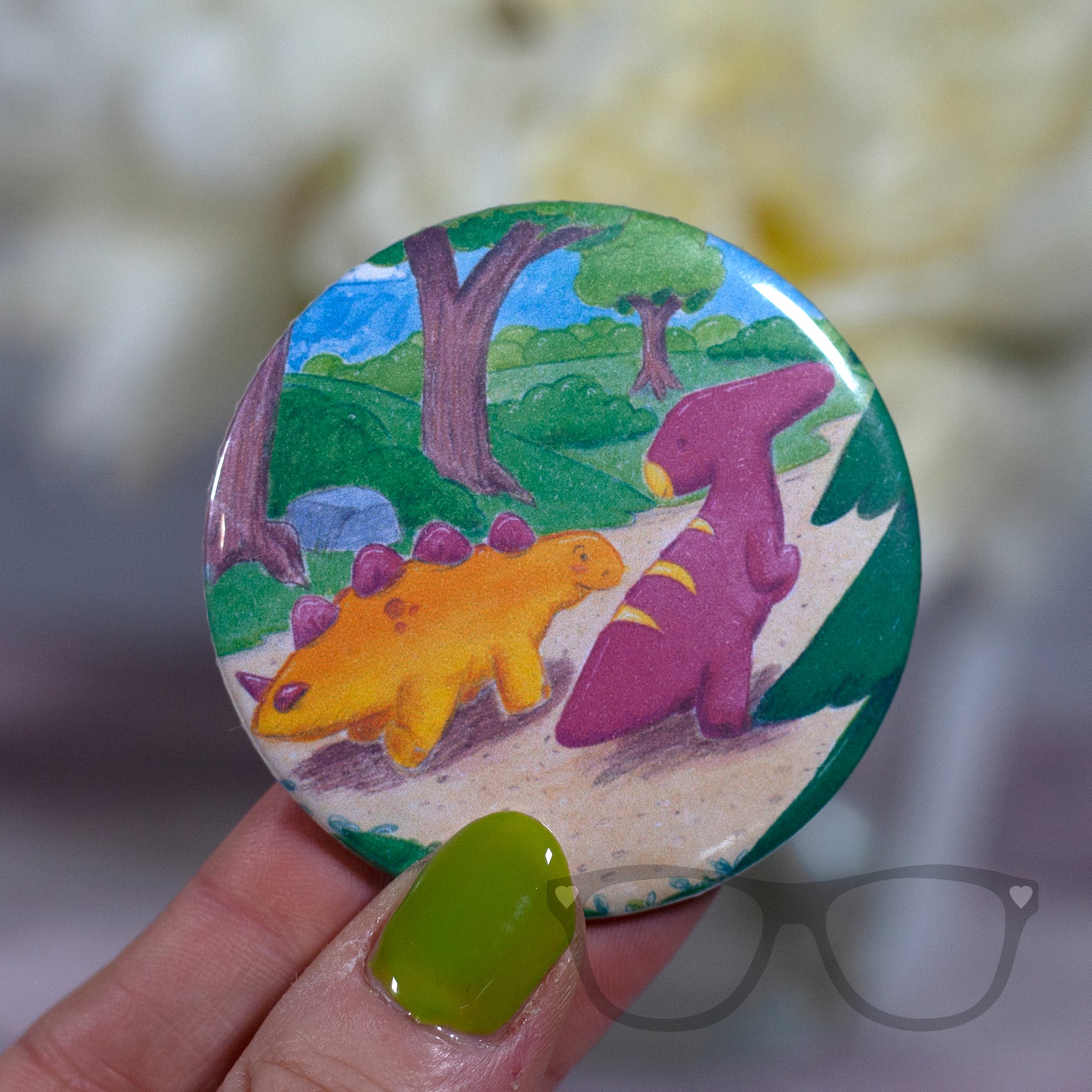 This 58mm badge shows the illustration of Derek and Irene the dinosaurs starting off on their adventure.