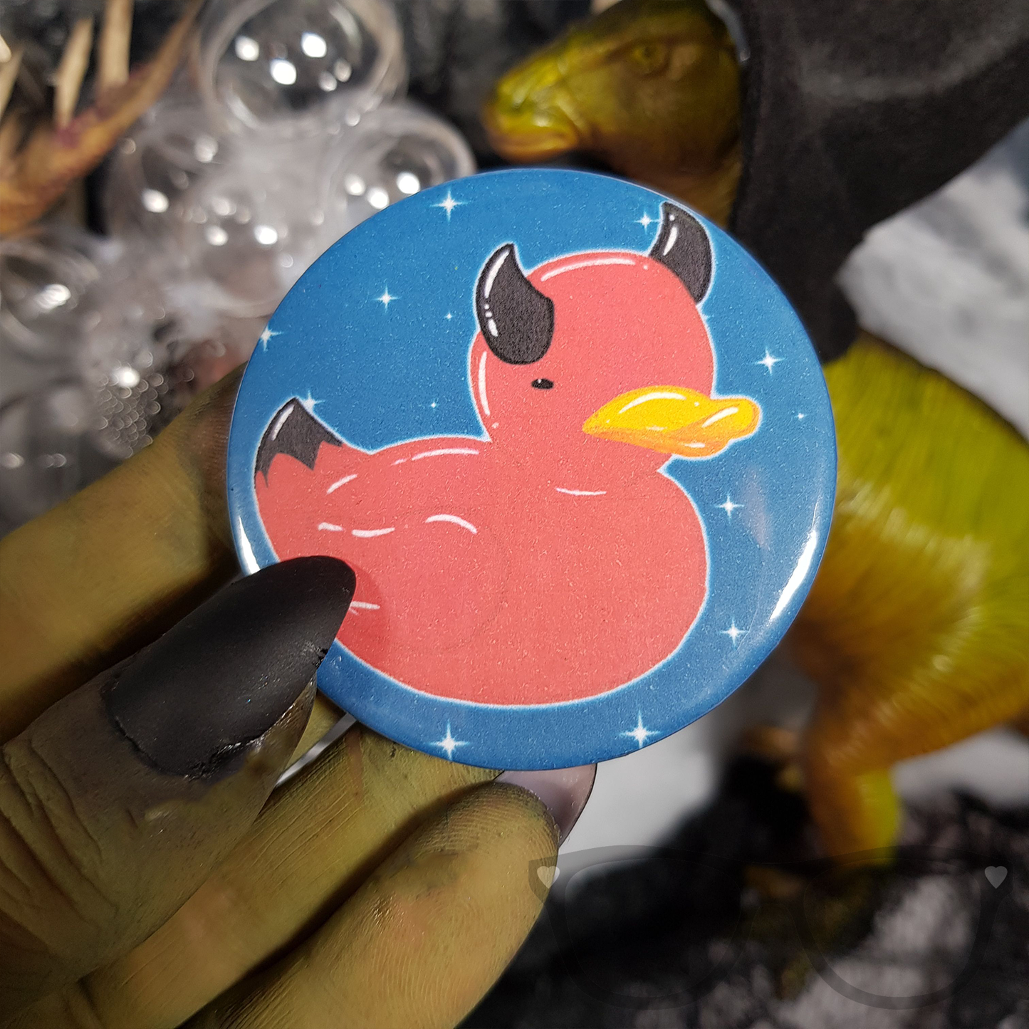 Beelzeduck 58mm badge, great as a treat for Halloween. Badge is being held by a witchy hand.