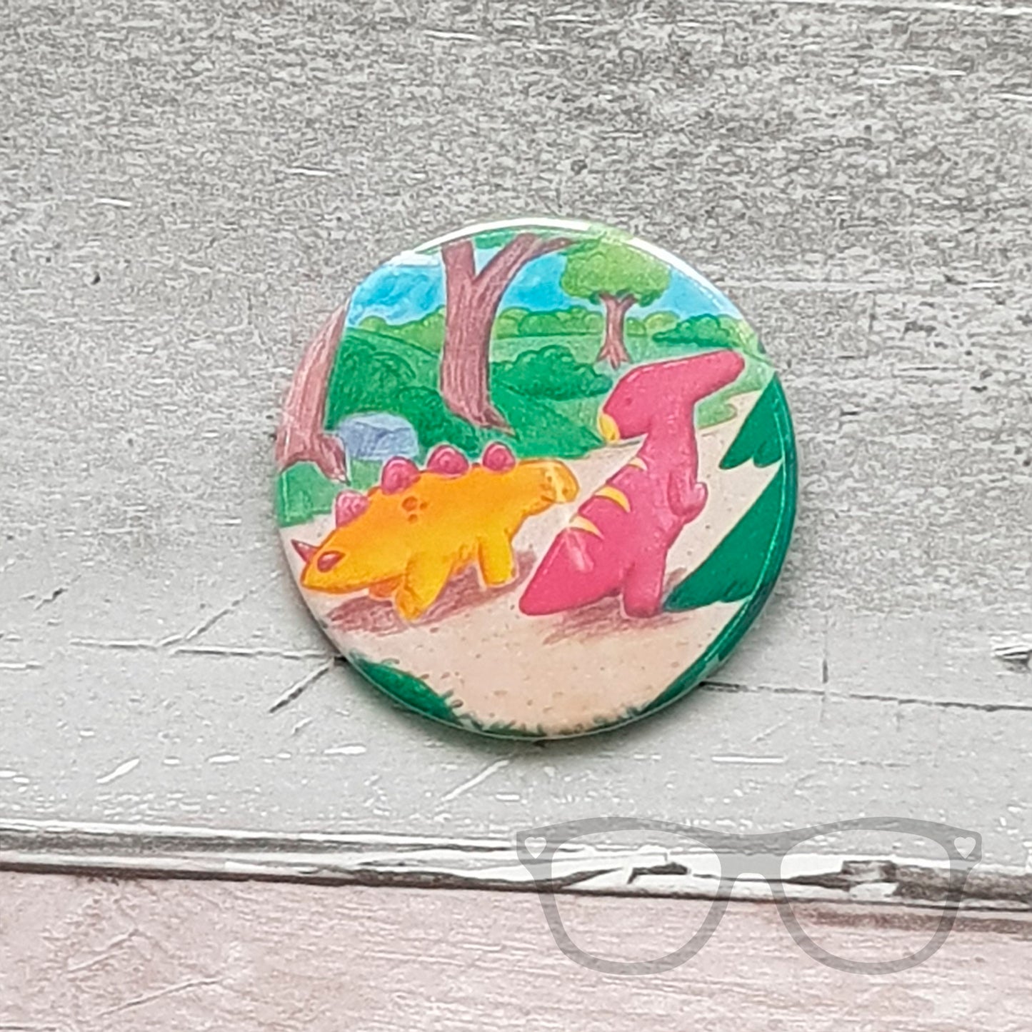 This 58mm badge shows the illustration of Derek and Irene the dinosaurs starting off on their adventure.
