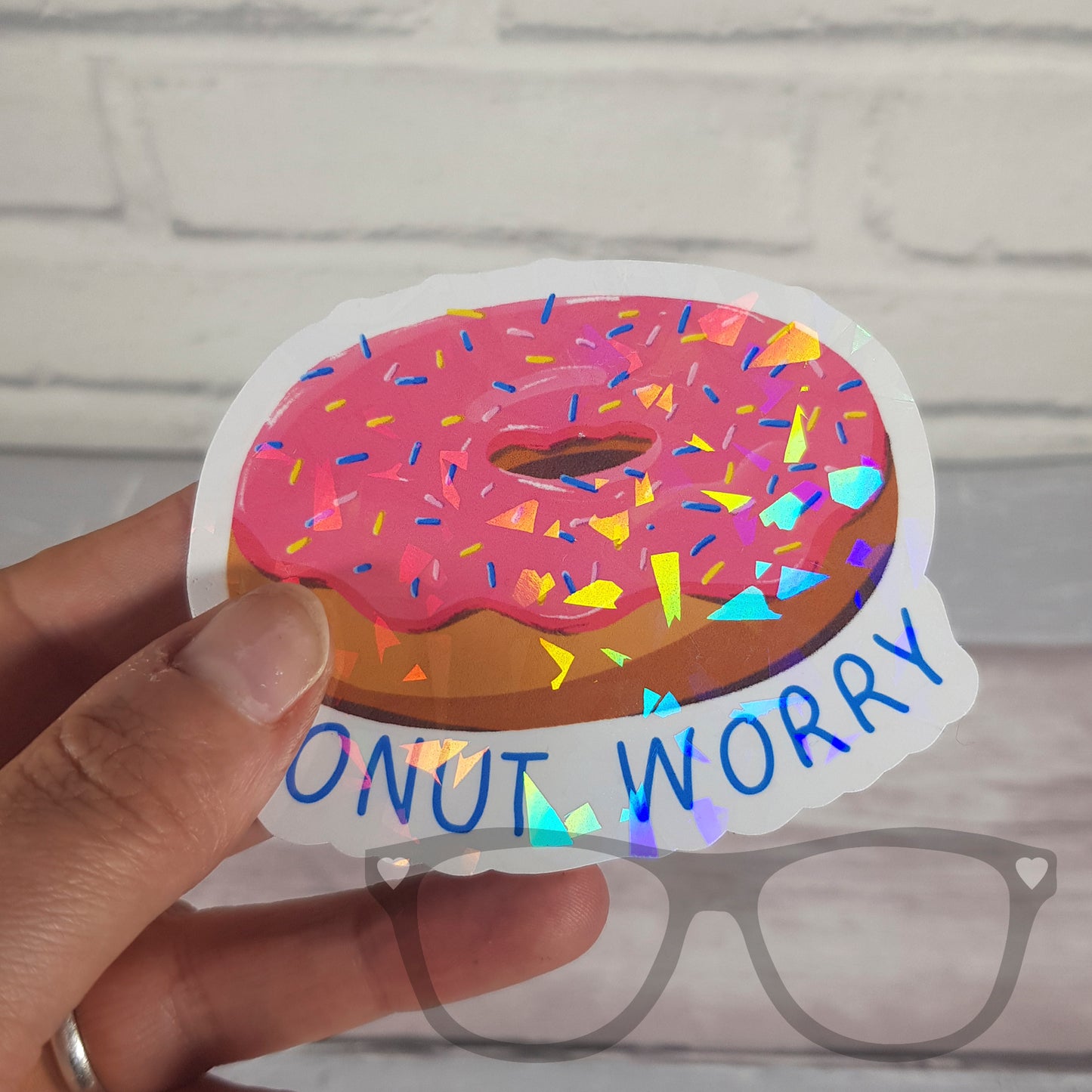 Sparkling pink 'Donut Worry' vinyl sticker being vinyl with cracked glass effect, perfect for decorating water bottles, notebooks, and more.