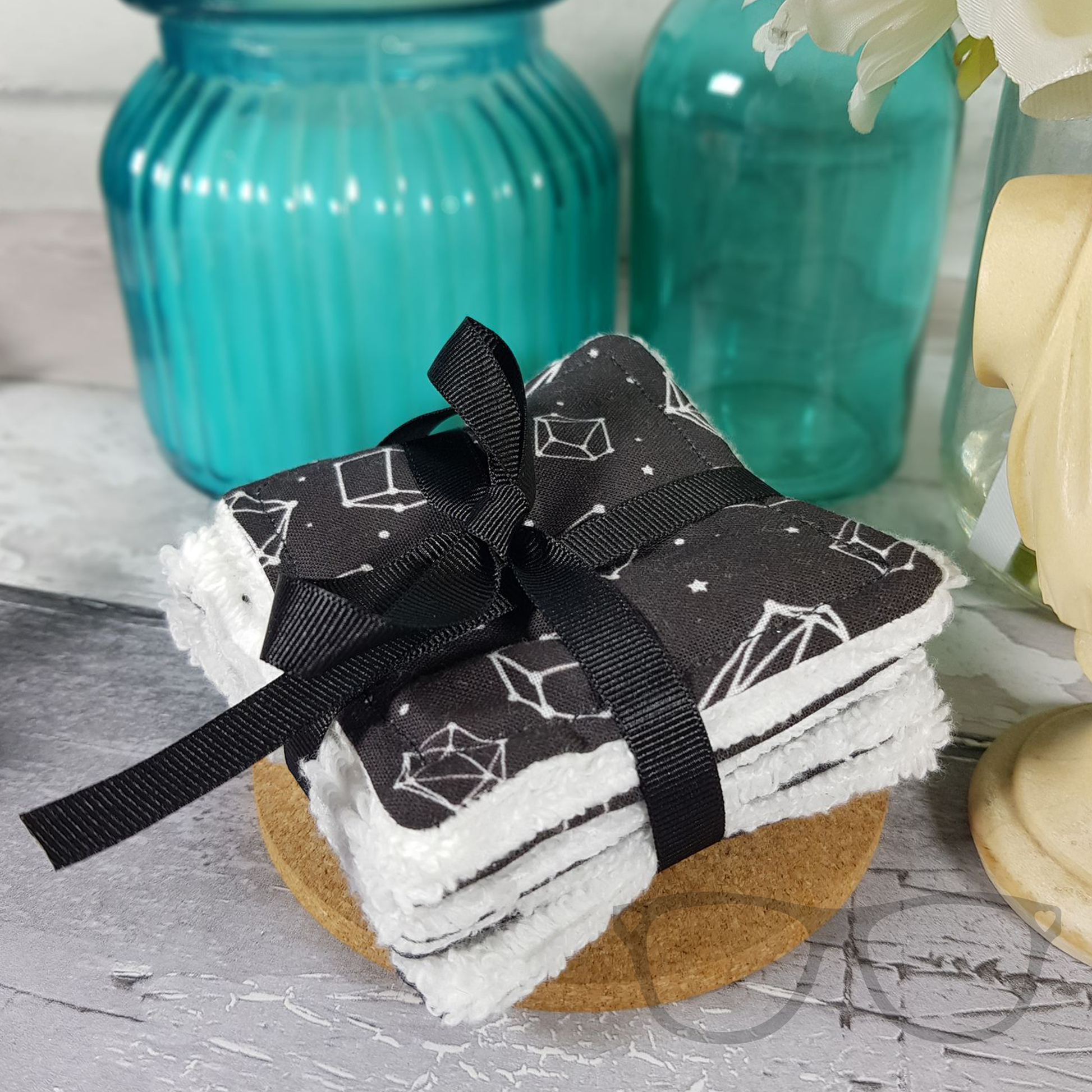 Square reusable face wipes in black fabric tied in a black ribbon.
