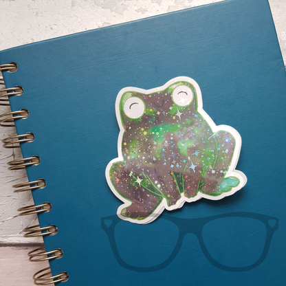 Green frog sticker with star sparkle on a notebook