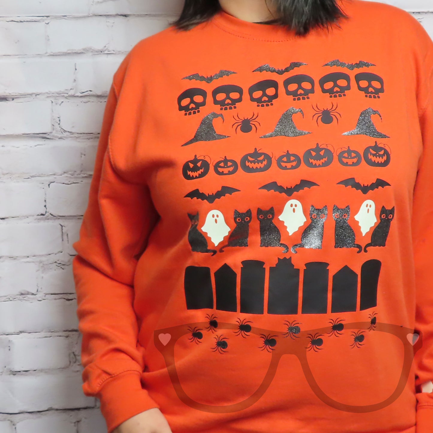 Orange sweater with cute halloween icons such as pumpkins, jack o'lanterns, gloe in the dark ghosts, spiders and glittery hats