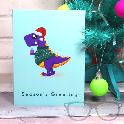 Christmas Dinosaur Card featuring Mama Rex wearing her festive jumper and holding a present. 