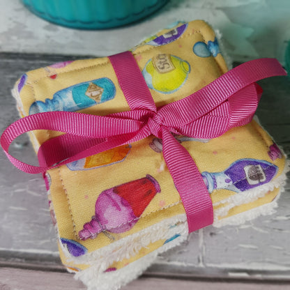 Reusable facewipes great for make up removal or cleansing your face. Pattern is a showing different types of potion bottles on a light yellow background wrapped in a pink ribbon